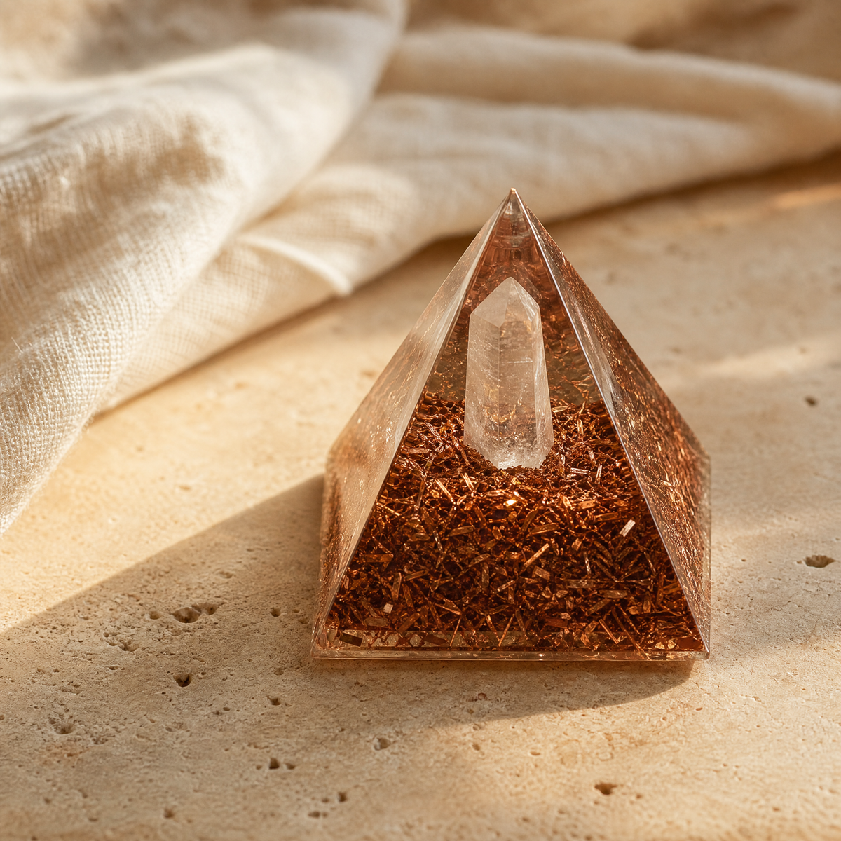 Pyramide d'orgonite en résine avec copeaux de cuivre et quartz, sur travertin